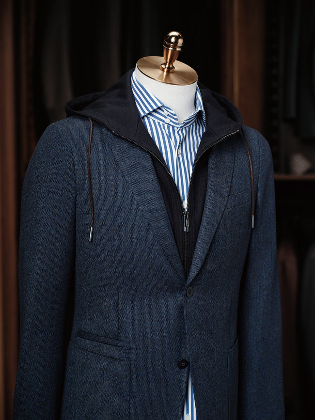 Close-up of a navy tailored blazer with hoodie details and blue striped shirt, showcasing modern tailoring by POLLHEIM. Ideal for casual yet refined fashion styles.