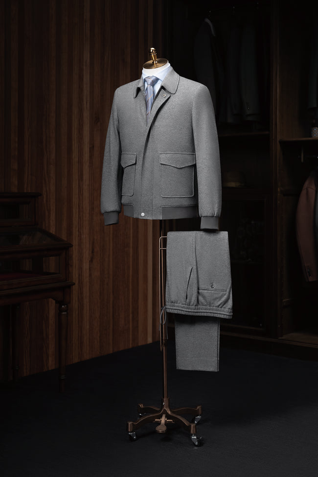 Full look featuring a grey wool bomber jacket and matching drawstring trousers, styled with a dress shirt and tie — a sophisticated twist on relaxed tailoring.