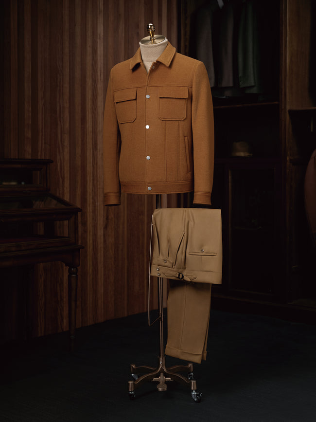 Full outfit on mannequin featuring a camel aviator wool jacket styled with mustard pleated trousers — a sleek, modern take on utilitarian menswear.