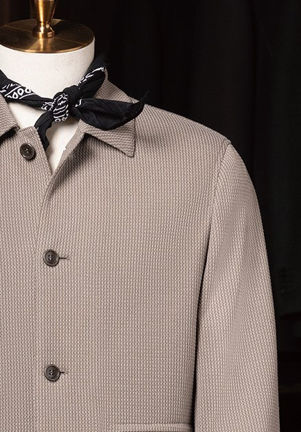 Stone grey textured jacket styled with black and white bandana around the neck on mannequin, highlighting a refined yet casual look.