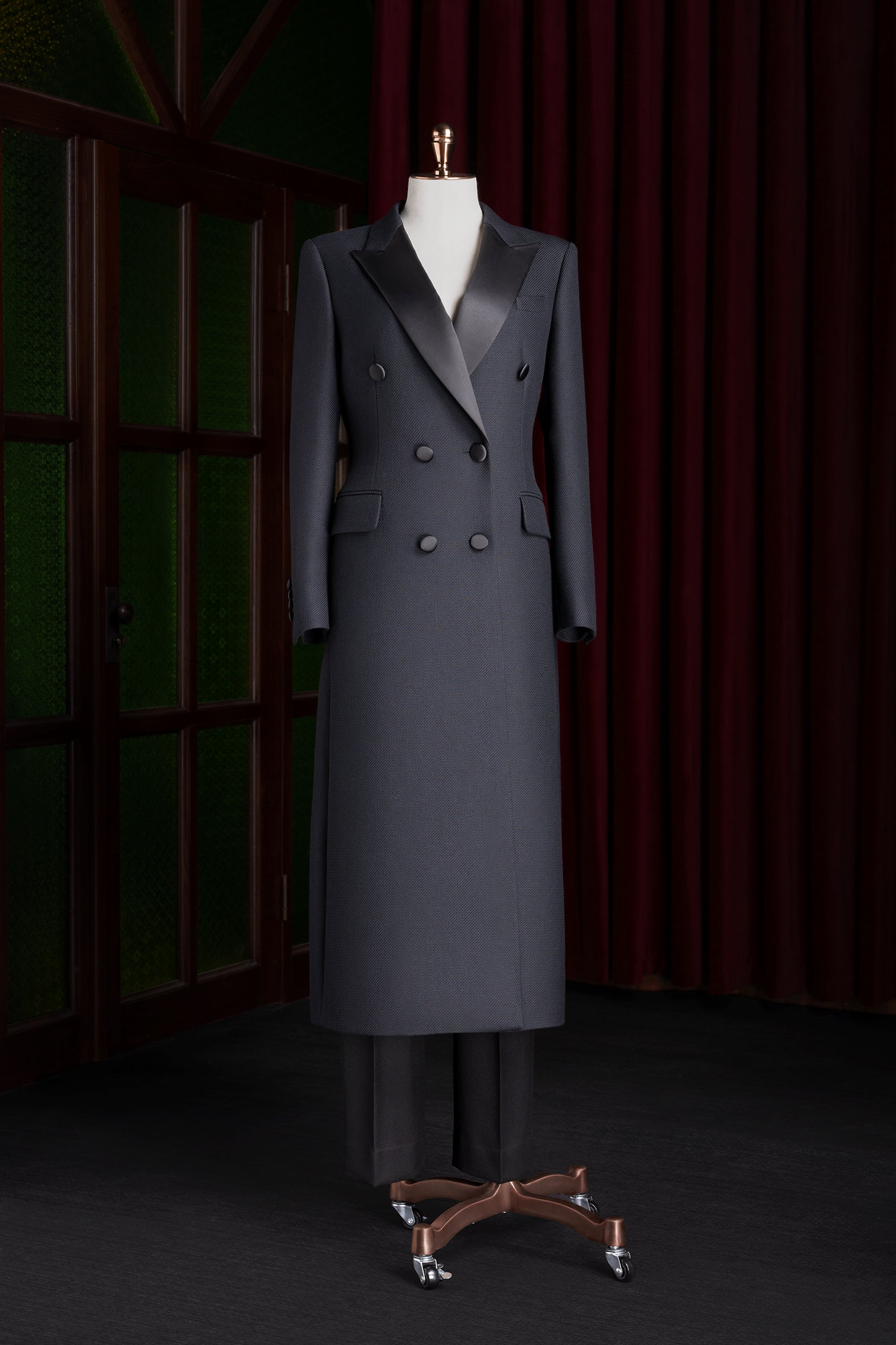 Women's long double-breasted black coat with satin lapels, tailored for formal events, showcasing high-end luxury and sustainable craftsmanship.