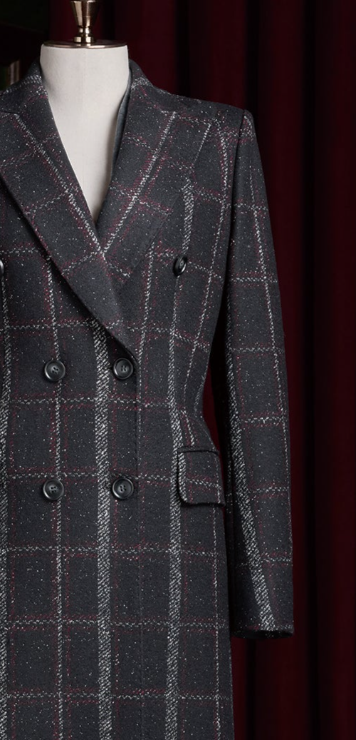 Close-up of women's double-breasted plaid overcoat in black with red and white accents. Sustainable, eco-friendly design for sophisticated formal style.