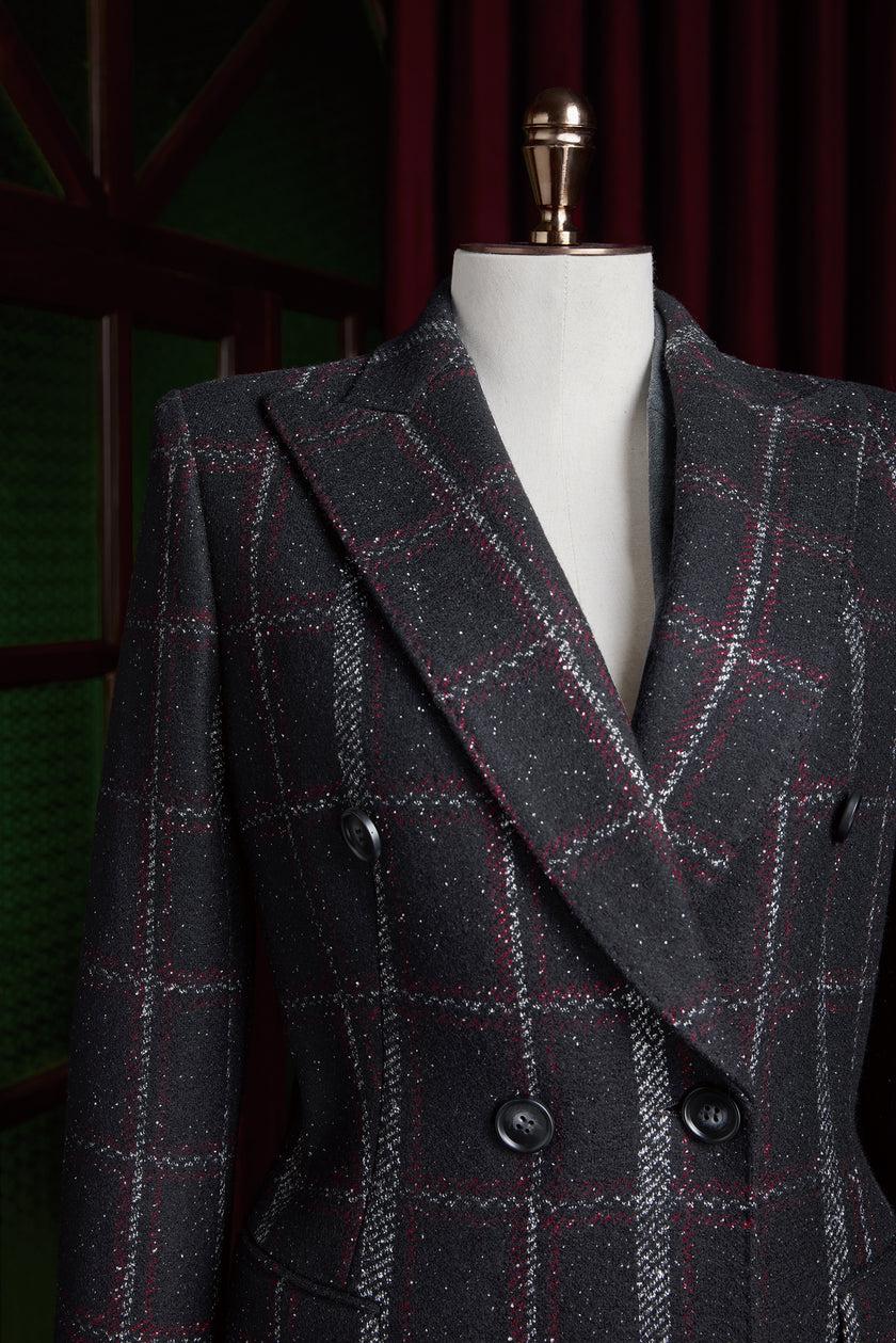 Close-up of black plaid women's overcoat with red and white accents, double-breasted design for formal wear, crafted with sustainable materials.