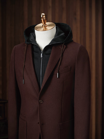 Close-up of men's burgundy blazer with single-button closure, layered over a black zip-up hoodie. Ideal for a sophisticated, casual look blending comfort and style. Perfect for eco-conscious individuals who value high-end, sustainable fashion.