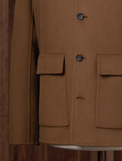 Close-up of camel tailored men's jacket with flap pockets and classic buttons, crafted from sustainable fabric for an eco-conscious and refined look.