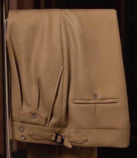 Close-up of camel tailored trousers with adjustable side tabs and buttoned pockets, crafted from premium sustainable fabric for a refined, eco-conscious style