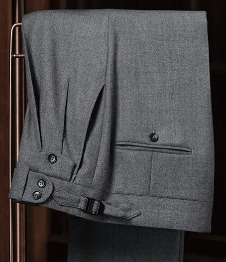 Close-up of grey tailored trousers by POLLHEIM, highlighting adjustable waist tabs and detailed stitching. Perfect for a refined, modern look with superior craftsmanship