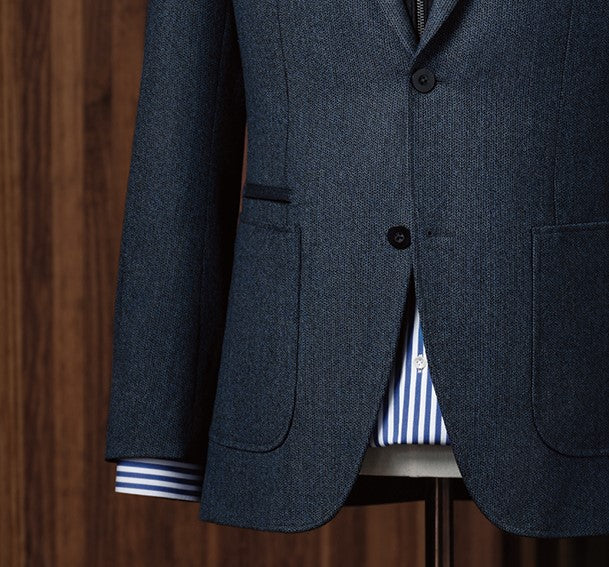 Close-up of navy blazer showcasing button details and pocket stitching by POLLHEIM. Modern tailoring that blends casual elegance and craftsmanship.