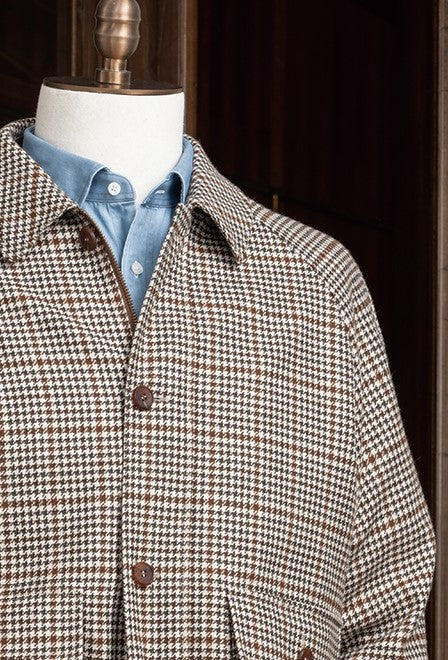 Close-up of houndstooth sports coat collar and shoulder paired with a blue shirt, showcasing sustainable fabric and tailored elegance for formal occasions.