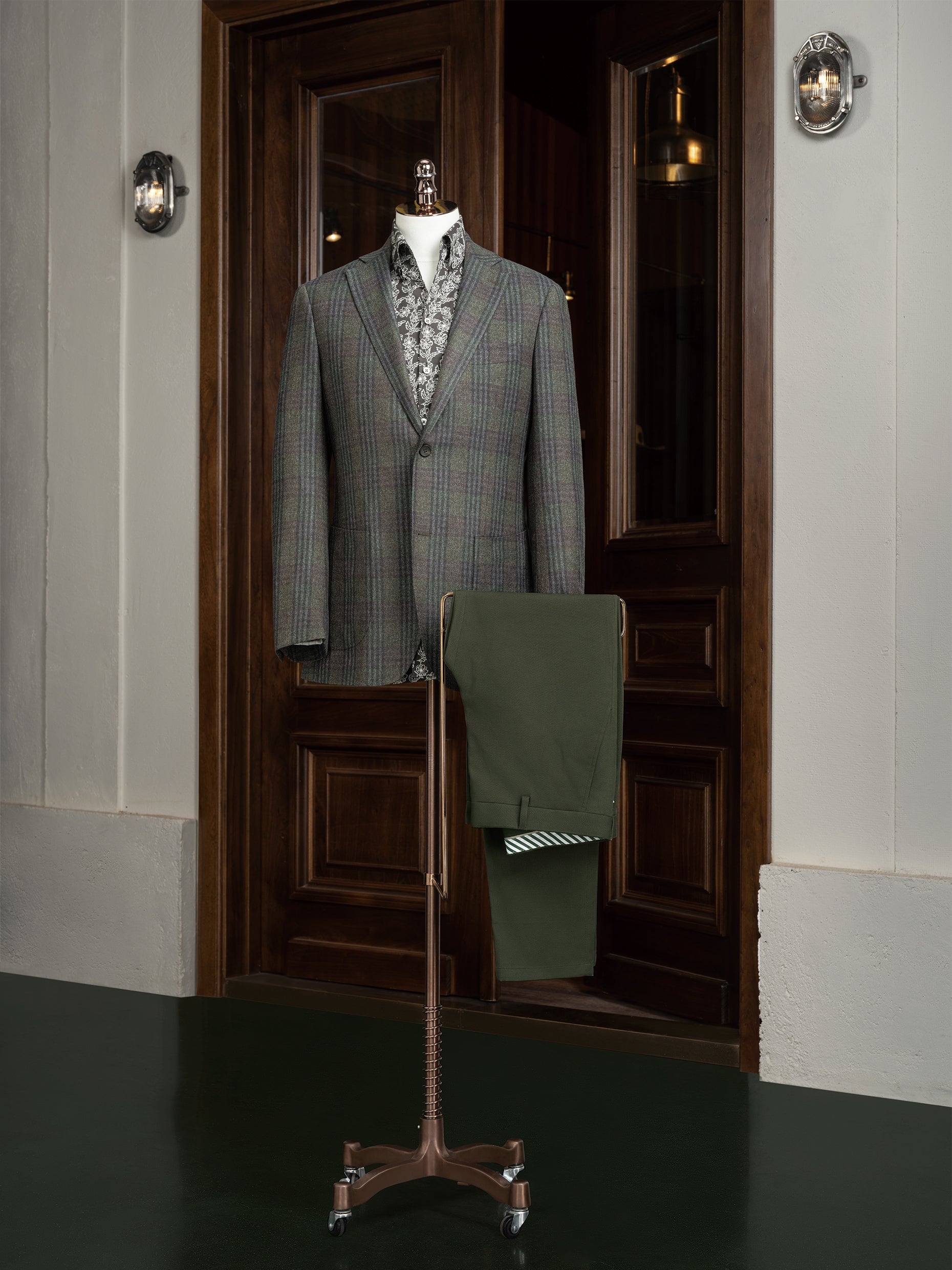 Tailored checked wool jacket paired with olive trousers on a mannequin, showcasing sustainable, high-end fashion perfect for formal elegance and eco-conscious style.