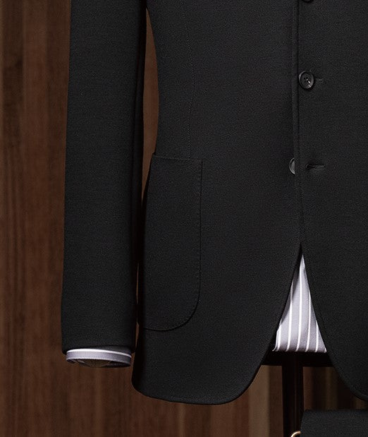 Close-up of tailored suit sleeve with buttons, highlighting fine stitching and sustainable craftsmanship for a refined, formal look.