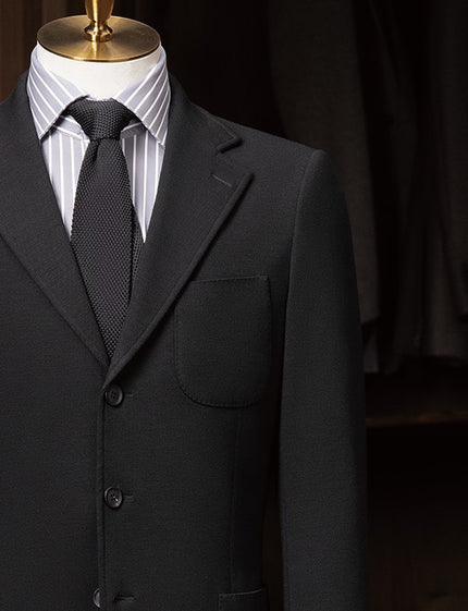 Close-up of black suit pocket and lapels, featuring tailored details and high-quality fabric, ideal for sophisticated formal occasions.
