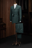 A stylish deep green suit displayed on a mannequin, featuring a belted jacket and formal trousers, perfect for elegant formal events. Made with sustainable materials.