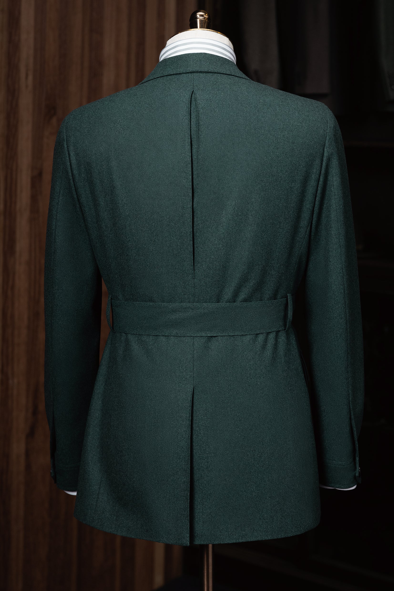 Rear view of the green suit jacket, revealing a structured belt detail that enhances the silhouette, embodying sophistication with eco-conscious design.