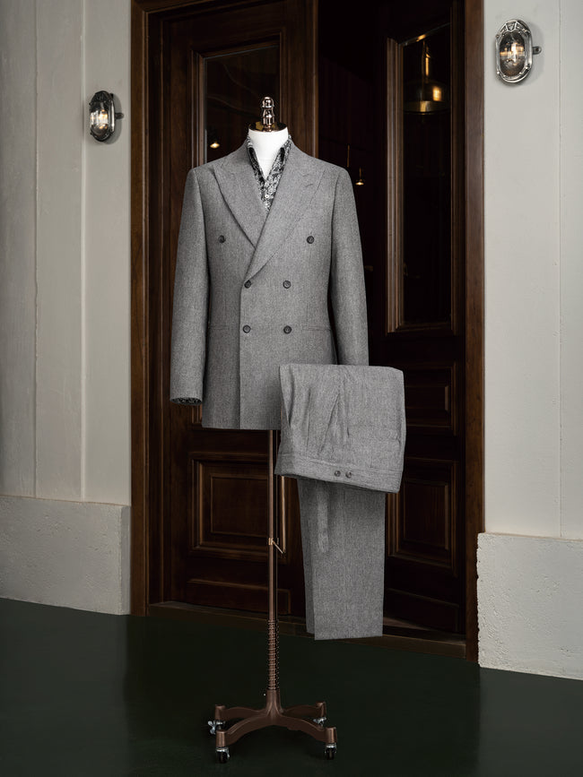 Elegant grey double-breasted suit on a mannequin, showcasing high-end tailoring for men. Perfect for formal events, crafted with sustainable materials.