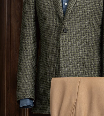 Close-up of the green checked jacket’s button detailing and precisely stitched sleeves, showcasing luxury craftsmanship and timeless style.