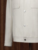 Close-up of The Couturist's white tailored jacket, highlighting snap button closure and front patch pockets. Luxurious women's tailored garment.