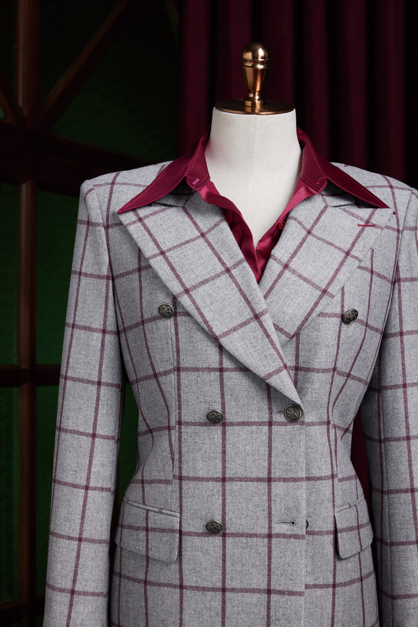 Close-up of a women's double-breasted grey check blazer showcasing wide lapels and maroon shirt beneath for a bold contrast.