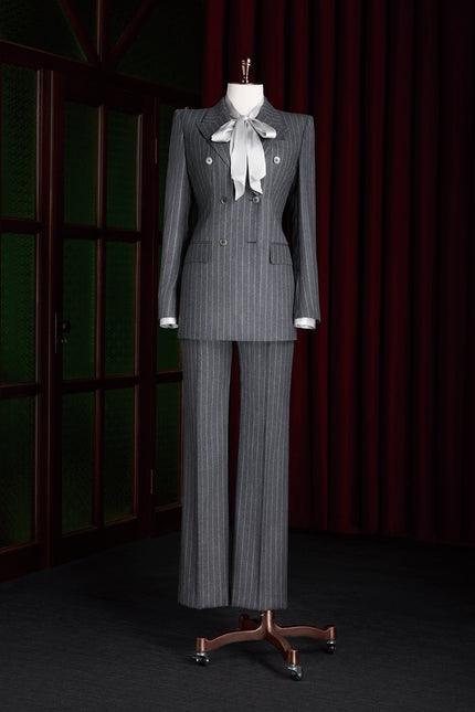 Elegant women's grey pinstripe wool suit with matching jacket and trousers, paired with a satin bow blouse.