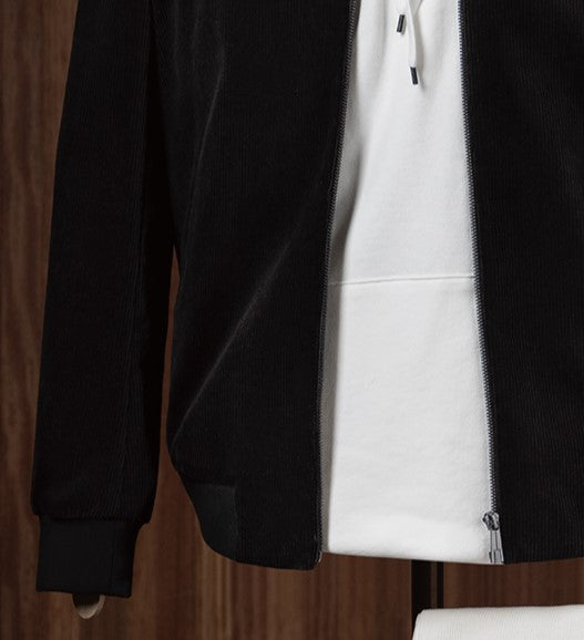 Stylish casual outfit featuring a black tailored zip-up jacket layered over a white hoodie and paired with cream-coloured trousers, displayed on a mannequin for modern streetwear style. Close-up on the zip and sleeves of the jacket 