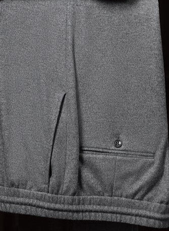 Close-up of grey wool drawstring trousers with an elastic waistband and buttoned welt back pocket — merging tailoring comfort with streetwear versatility.
