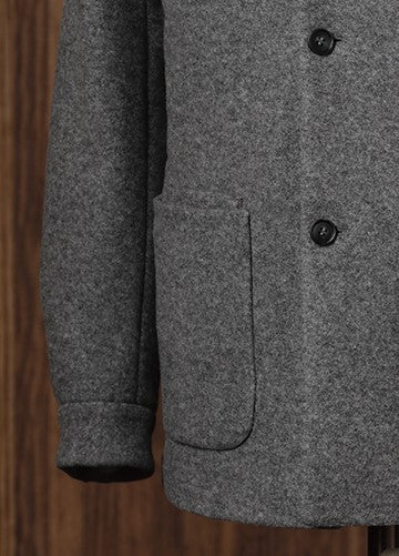 Lower half of a grey wool jacket with oversized patch pocket and clean cuff finish — highlighting tailored functionality and everyday layering potential.