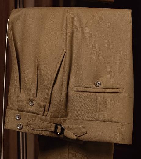 Close-up of mustard pleated trousers with back welt pocket, double side adjusters, and buckled waist tab — crafted for a structured yet classic silhouette.