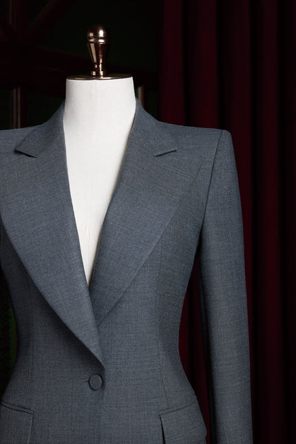 Close-up of a women's tailored grey blazer showing refined notch lapels and structured darting at the waist, highlighting clean craftsmanship.