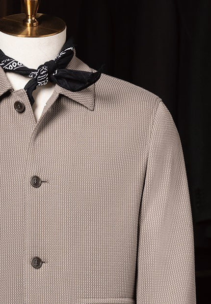 Stone grey textured jacket styled with black and white bandana around the neck on mannequin, highlighting a refined yet casual look.